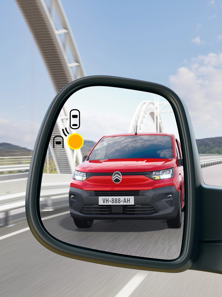 Berlingo Van rouge détecté dans le rétroviseur latéral avec le système de surveillance des angles morts signalant un véhicule dans la voie adjacente.