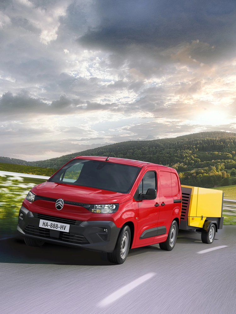 Berlingo Van tractant une remorque sur une route de campagne, illustrant la stabilité en remorquage.