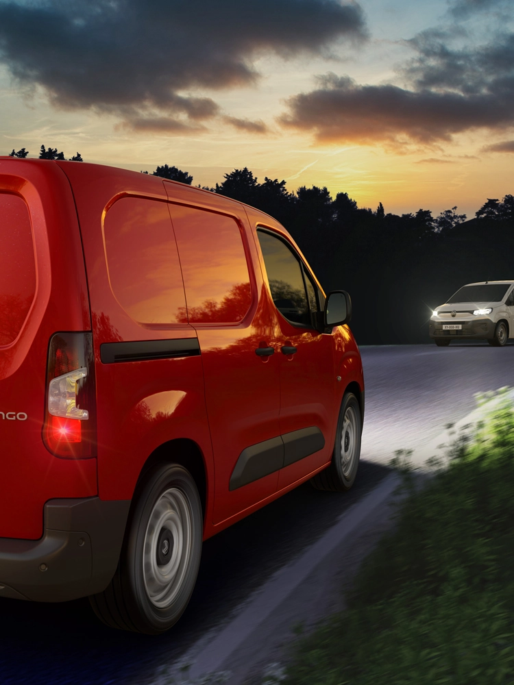 Berlingo Van rouge roulant de nuit sur une route de campagne, utilisant l’assistance automatique aux feux de route pour détecter les véhicules arrivant en sens inverse et ajuster l’éclairage.